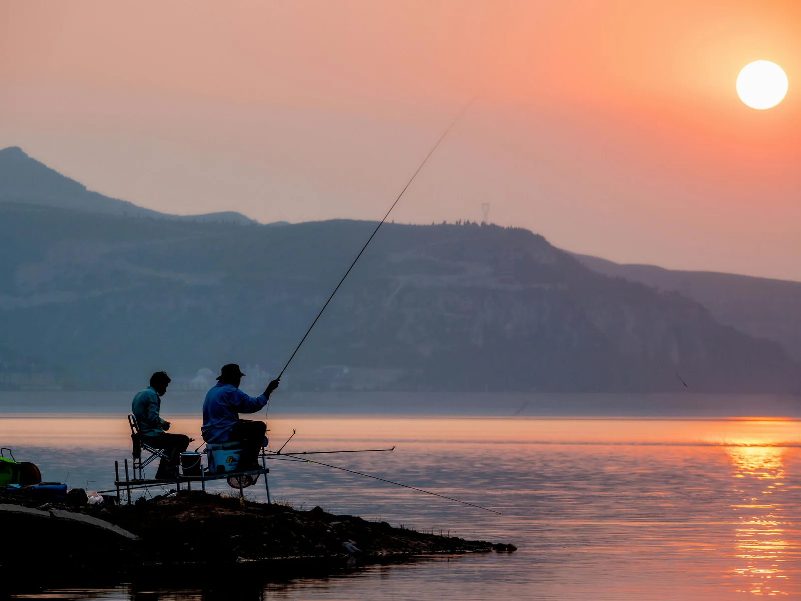 Pescadores de spinning junto al agua al atardecer para ilustrar el calendario anual